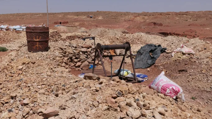 Vanadinit-Mine in der Region Midelt in Marokko mit einem einfachen Fördermechanismus über einem Schacht, umgeben von rötlichem Gestein.