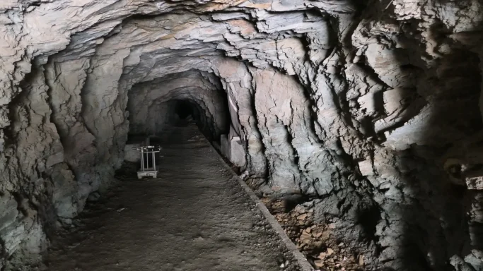 Innerer Stollen der historischen Blei-Silber-Mine Ahouli in Marokko mit zerklüfteten Felswänden, schmalem Laufweg.